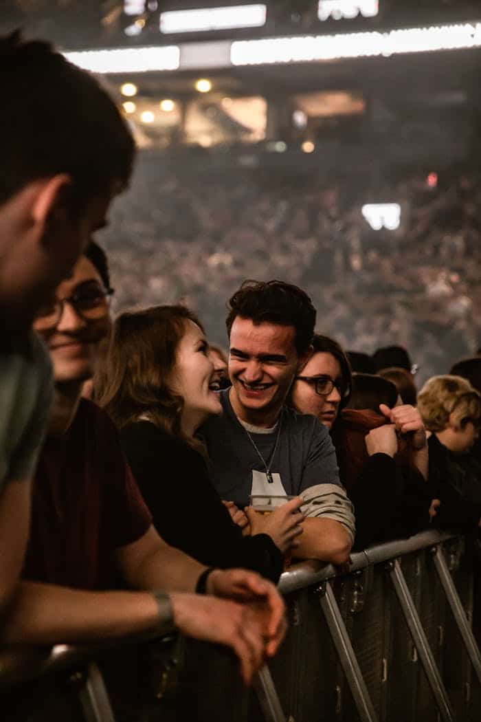 A lively crowd at a concert enjoying the performance with smiles and laughter.